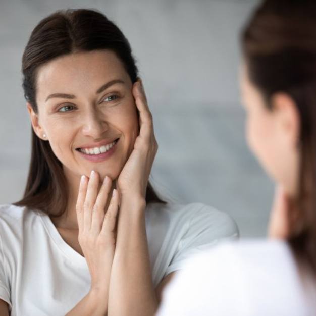 a woman smiling and touching her cheeks