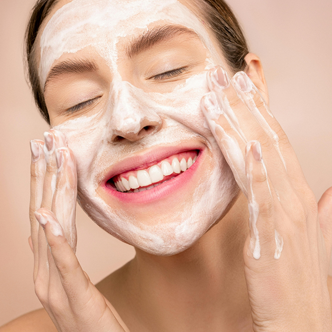 Smiling woman applying a CUVGET skin care cream to her face