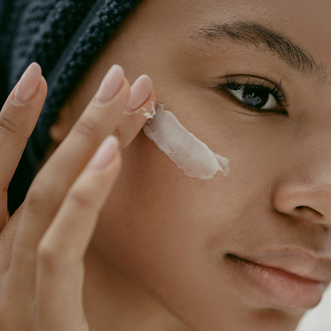 Woman placing a strip of white cream on her cheeks