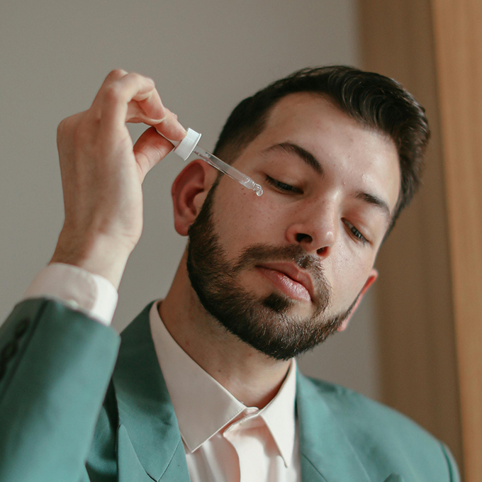 Man using a dropper to apply a serum to his face