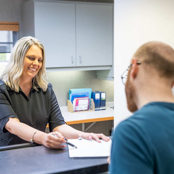 Receptionist showing a patient where to sign on a clipboard