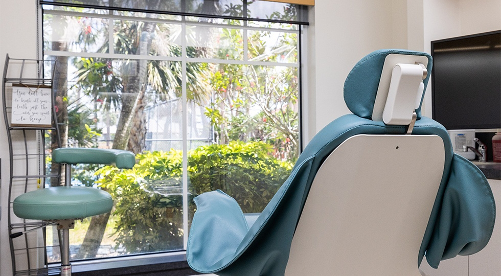 Dental exam room with palm trees visible out of the window