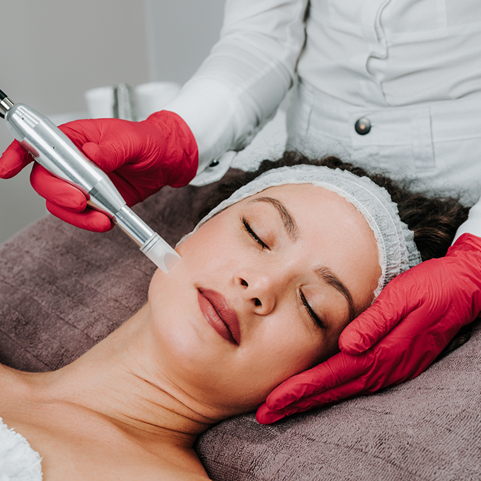 Esthetic doctor holding a pen like device to a womans cheek