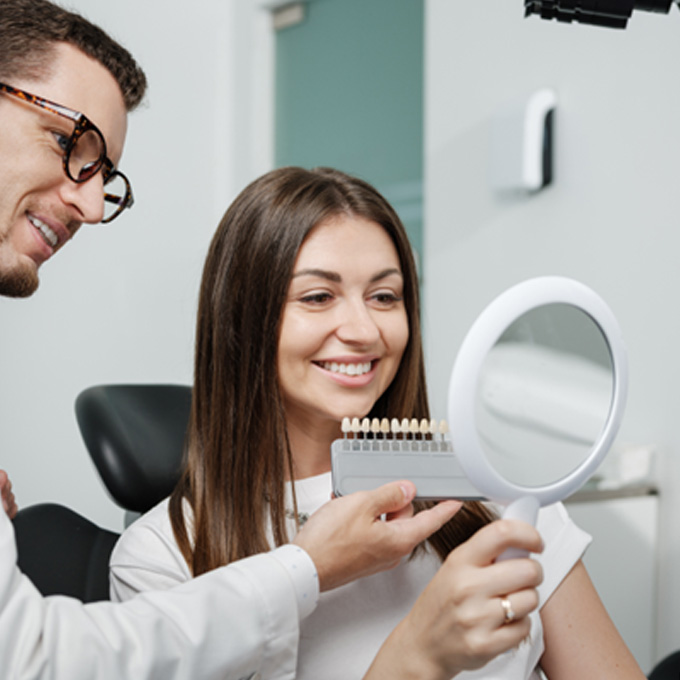 Dentist showing smiling patient shade scale