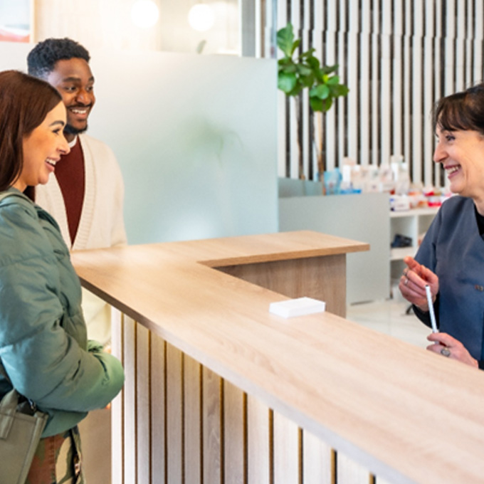 Smiling patients talking to dental assistant in lobby